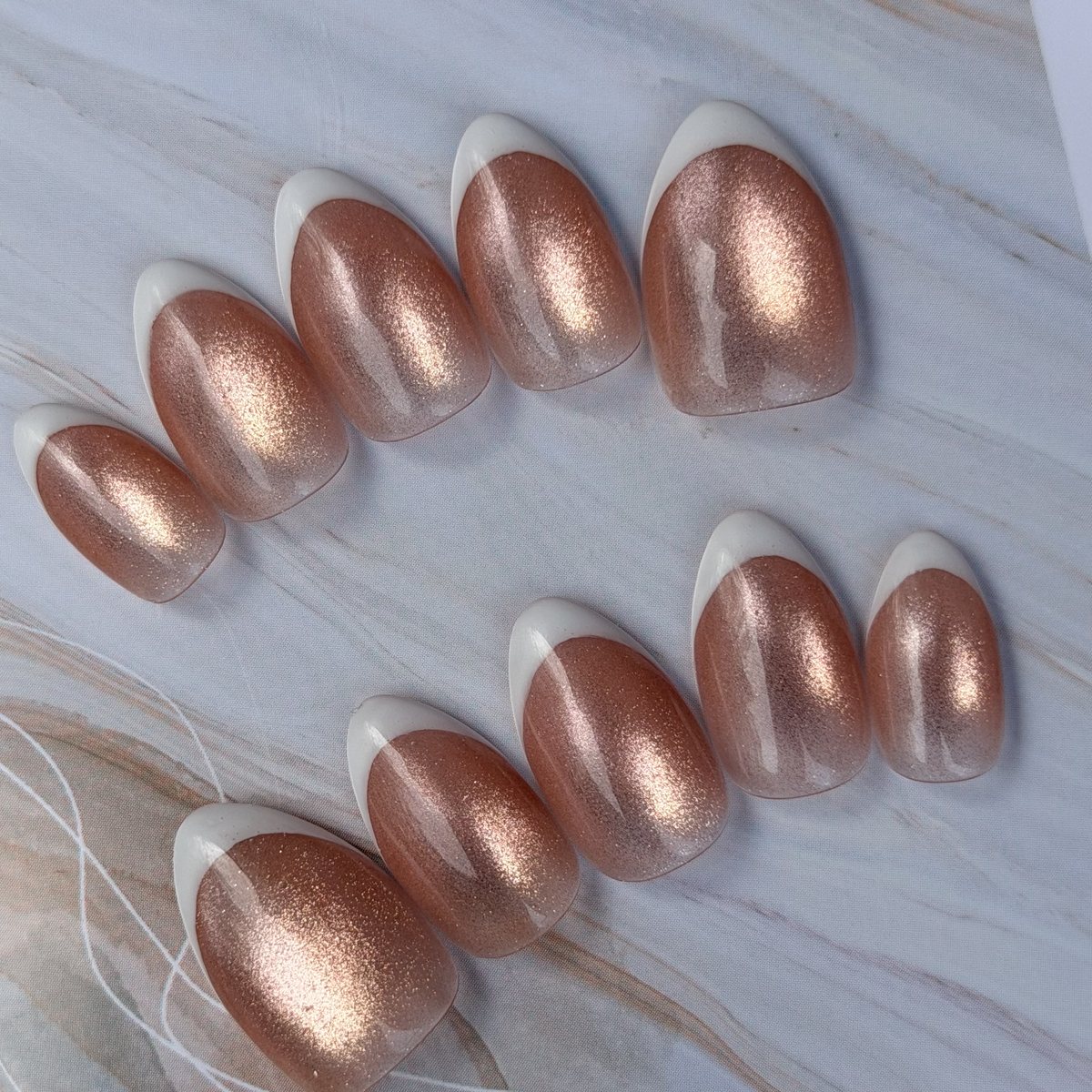 Ten short almond press-on nails in rose-gold shimmer with white French tips